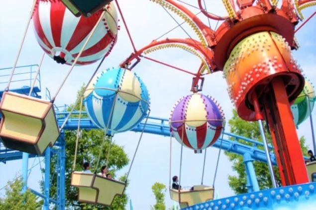 観覧車のような乗り物に乗り、楽しんでいる人々。