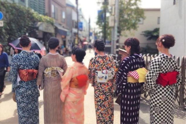 リゾートバイトの休日に観光するイメージ画像。浴衣を着た女性たちが、温泉街を散策している後ろ姿。