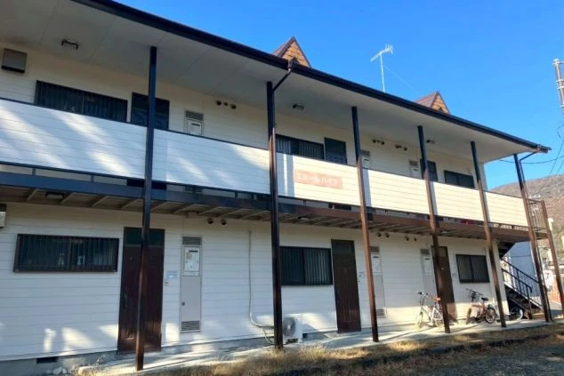 リゾートバイト住み込み求人の個室寮外観。青空に映えるアパートタイプの建物で、一人暮らし感覚の生活。