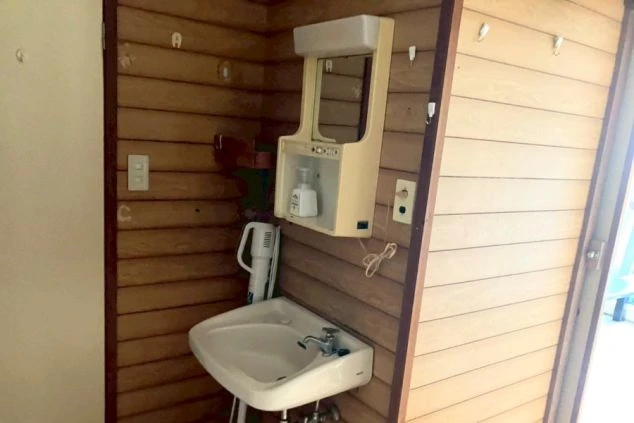 リゾートバイト寮の独立洗面台。鏡と手洗い場があり、朝の身支度がスムーズにできる。温かみのある落ち着いた内装。