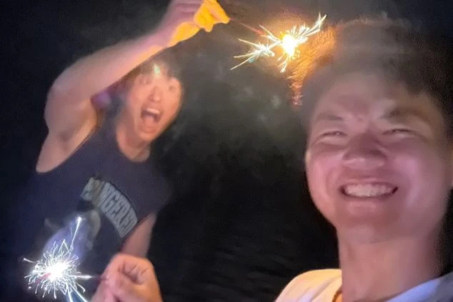 夜の砂浜で手持ち花火を楽しむ2人の男性の画像。花火の光に照らされた楽しそうな笑顔が印象的で、リゾートバイトで出会う友人との友情や、夏の夜の思い出を想起させる。