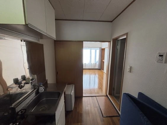 リゾートバイトの個室寮のキッチンの画像。白い壁と棚、ステンレス製のシンクがあり、冷蔵庫とコンロが備え付けられている。リゾートバイトの寮の共用キッチンの画像。