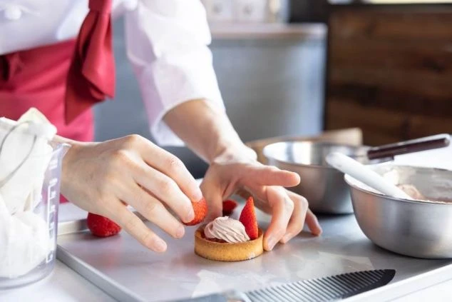 イチゴを乗せてケーキを飾り付けするパティシエ。お菓子作りが好きな方におすすめの、リゾートバイトです。
