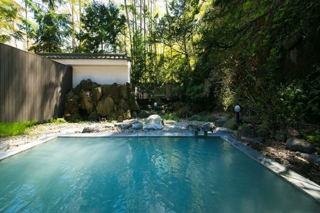 新緑の美しい大自然に囲まれた露天風呂の写真。リゾートバイトの仕事終わりに、温泉でゆっくりと疲れを癒せるという魅力を伝えます。