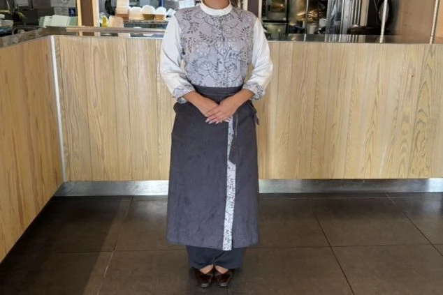 リゾートバイトの仕事風景を表現するイメージ画像。レストランのホールの仕事で着用する、花柄のシャツと黒いエプロン。