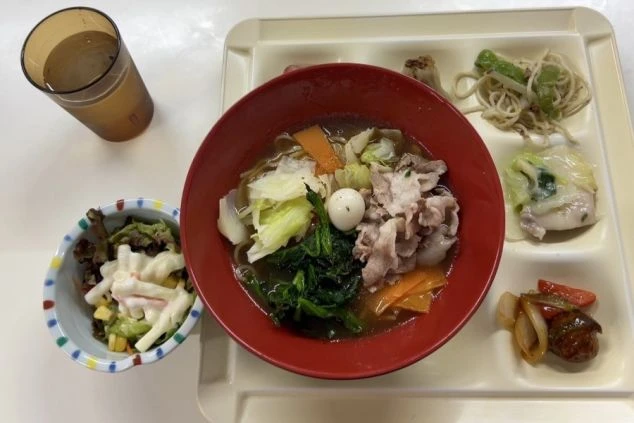 ラーメンがあり、他にマカロニサラダ、焼きそば、ソーセージと玉ねぎ炒め、水などが付いている。