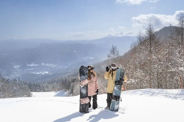 ゲレンデの山頂に立つスノーボーダー。絶景を楽しみながら働ける、冬のリゾートバイトです。
