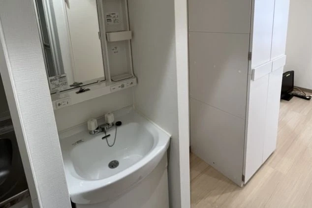 リゾートバイトの寮の独立洗面台。鏡付きの洗面台と収納があり、清潔感のある設備。