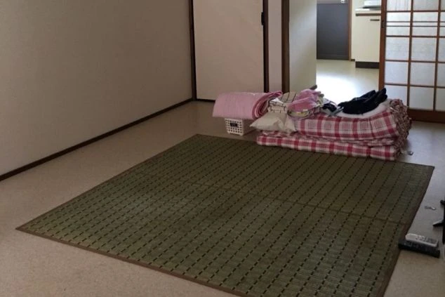 リゾートバイトの男性寮の室内。テレビと折りたたみベッド、布団が備え付けられており、プライベートな空間が確保されています。