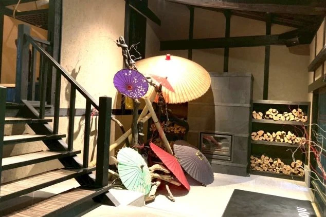 豊かな紅葉と竹林に囲まれた、黒い建物の施設外観。