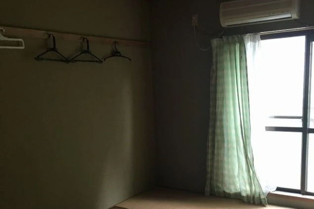 リゾートバイトの個室寮の寝室。エアコンが完備されており、ハンガーラックも設置されています。窓からは自然光が入り、明るく過ごしやすい空間です。