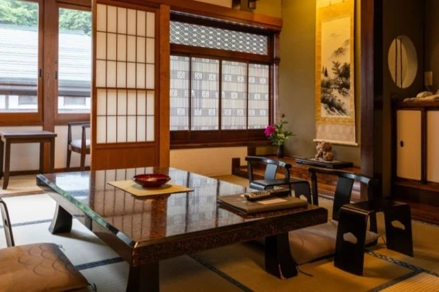 旅館の客室内部の写真。座卓や座椅子が並んでおり、障子や床の間もある。