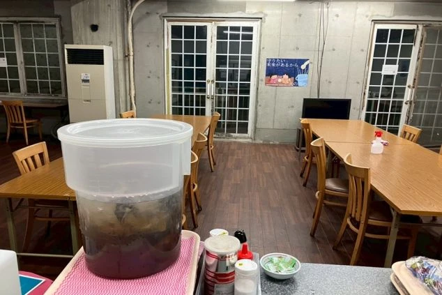 リゾートバイトの従業員食堂。木製のテーブルと椅子が並び、奥にはテレビも設置されています。手前には大きな冷水ポットが用意されています。