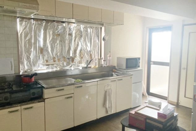 リゾートバイト寮のキッチン。ガスコンロ、シンク、電子レンジ、冷蔵庫が備え付けられ、自炊ができる設備の画像。