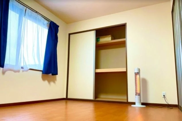 リゾートバイトの個室寮の室内。木目調の床にクローゼットとヒーターが設置されている。快適な生活環境をアピール。
