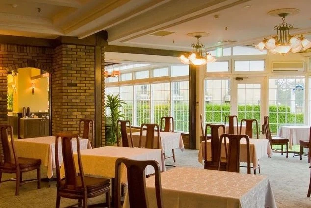 テーブルと椅子が並んだ、窓から光が差し込むレストランの画像。レンガの壁や照明が印象的で、おしゃれな空間。リゾートバイトの勤務地となるホテルのレストランや結婚式場を表す。