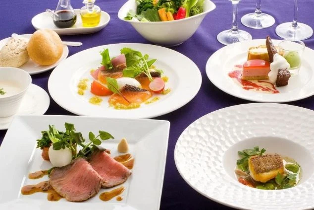 テーブルに並べられた豪華なコース料理の画像。前菜、メインの肉料理と魚料理、デザートなどが美しく盛り付けられている。