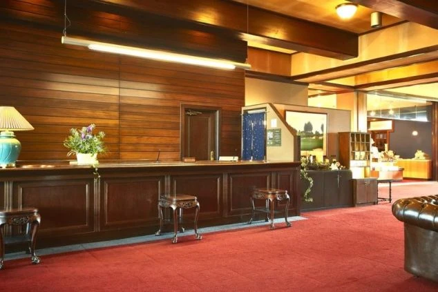 重厚な木製カウンターがあるホテルのロビーの画像。赤い絨毯が敷かれ、落ち着いた雰囲気が漂っている。リゾートバイトの勤務地となるホテルのフロントや、高級感のある職場を表す。