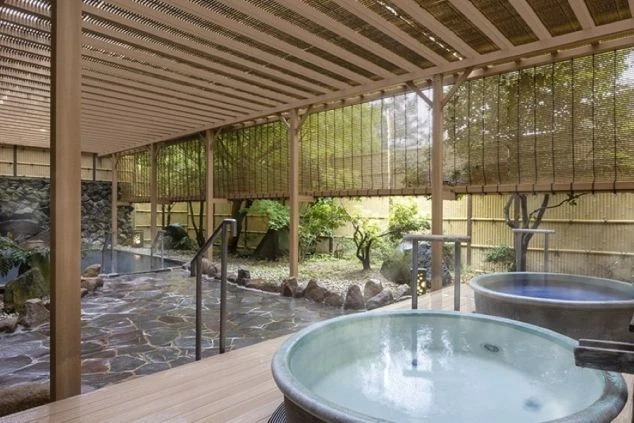 露天風呂の温泉の画像。和風の落ち着いた雰囲気の空間で、周りは木々や竹で囲まれている。リゾートバイトの寮やホテルの福利厚生としても利用できる、温泉の画像。