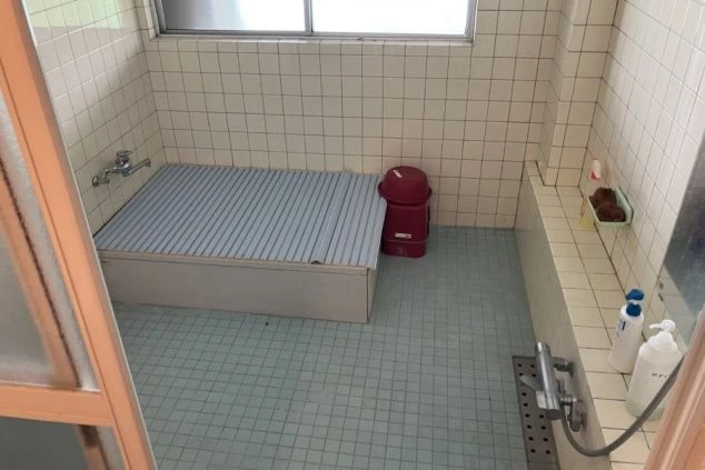 リゾートバイトの社員寮にある風呂のイメージ画像。青いタイル張りの床の、広々とした浴室。