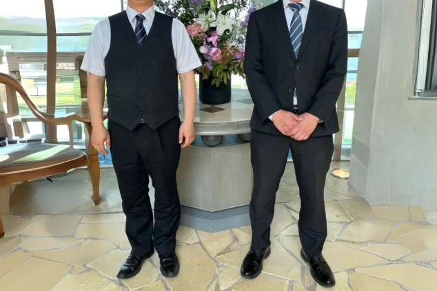 フロントの男性の制服画像。夏は半袖、冬は長袖のスタイル。