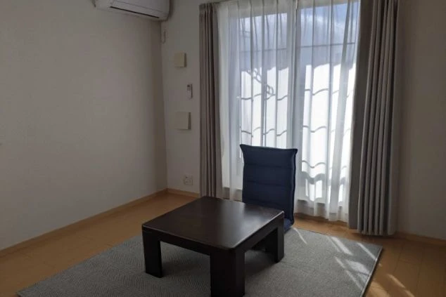 寮の個室。ローテーブルと座椅子、エアコンを完備。