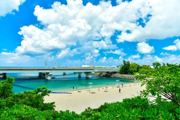 リゾートバイトの休日に観光するイメージ画像。白い砂浜とエメラルドグリーンの海、青い空が広がる沖縄のビーチ。