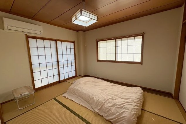 リゾートバイト寮の個室内部の画像。シングルベッド、エアコン、照明が完備された清潔感のある空間で、住み込みバイト中もリラックスして過ごせる。