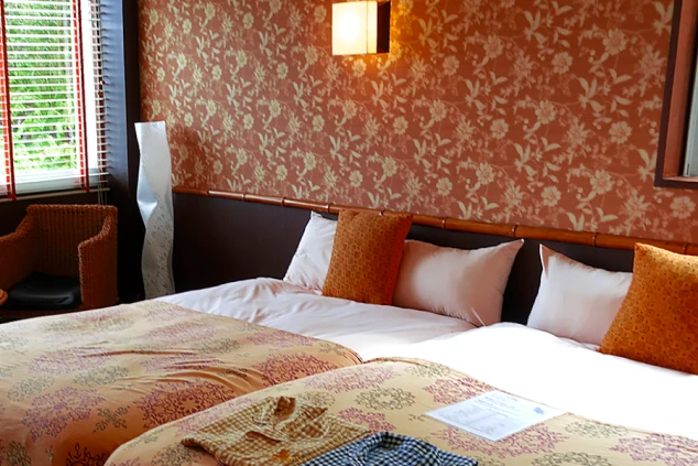 リゾートバイトの社員寮の部屋を表現するイメージ画像。ベッドが2つと、椅子や照明が備え付けられた洋室。