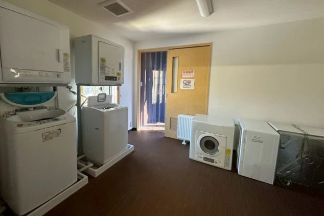 洗濯機と乾燥機が複数並ぶ、リゾートバイトの寮の共同洗濯室の画像。