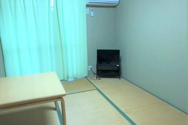 リゾートバイトの個室寮の和室。明るいカーテンと窓があり、開放的な雰囲気を演出。