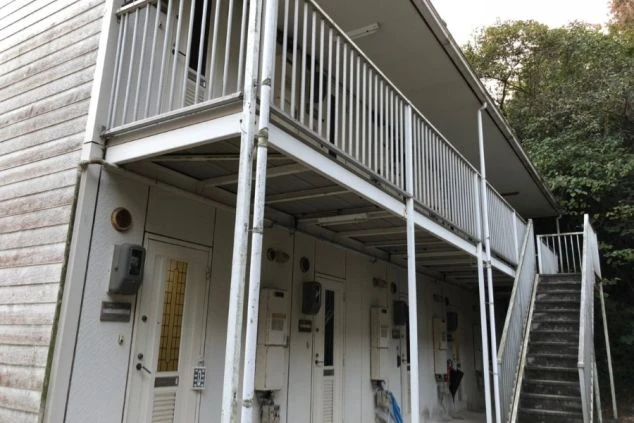 リゾートバイトの寮の外観。2階建てのアパートタイプで、各部屋の玄関と階段が見える。プライベートな空間が確保されていることをアピールする画像。