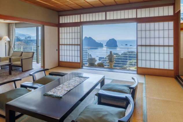 静岡県西伊豆にある堂ヶ島温泉の旅館の客室。障子戸を開けると、眼下に青い海と奇岩の絶景が広がる。リゾートバイトで働く場所から見られる景色をアピール。
