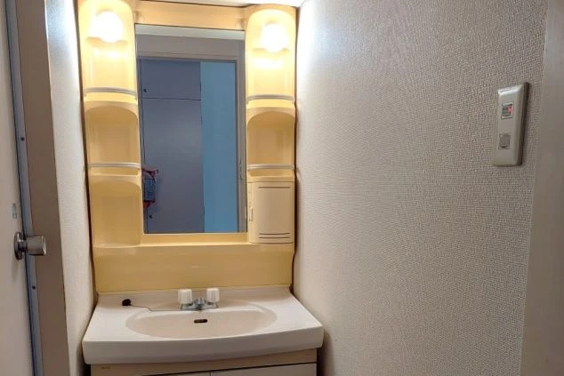 ワクトリの社員が出張で撮影した、リゾートバイトの寮の洗面台の画像。鏡と照明、収納棚が一体となったコンパクトな洗面化粧台で、清潔感のある空間。