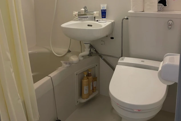 リゾートバイトの個室寮にあるユニットバス。浴槽、洗面台、温水洗浄便座付きのトイレが一体となった、清潔な設備の画像。