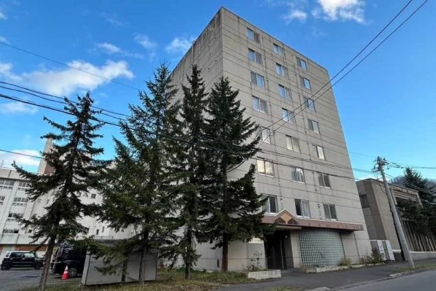 寮の外観。背の高い建物と並木、電線が映る。