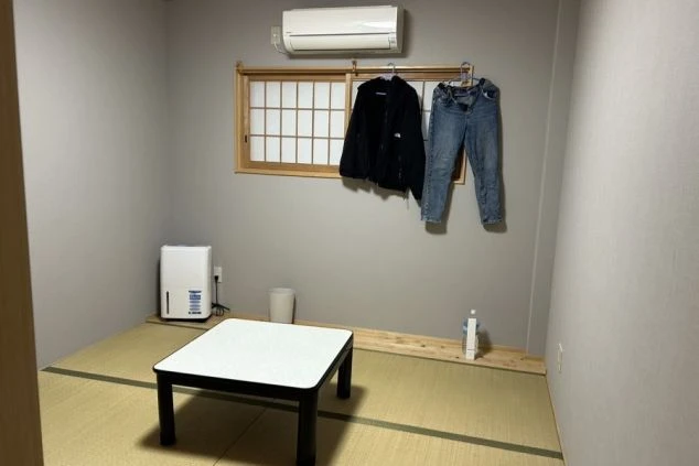 寮の個室。畳の床にローテーブル、加湿器、エアコン、障子付きの窓が映る。