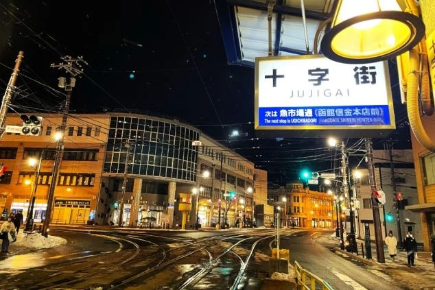 夕日を背景にしたシルエットの男性と、画面上部に「HOKKAIDO 函館 WORK TRIP」、下部に「絶品まかない3食無料」「温泉無料×完全個室寮」の文字が書かれている。