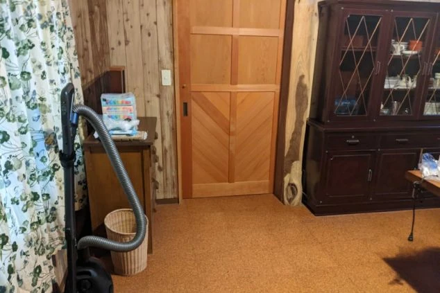 リゾートバイトの社員寮の共用スペースのイメージ画像。部屋の隅に掃除機や家具が置かれている。