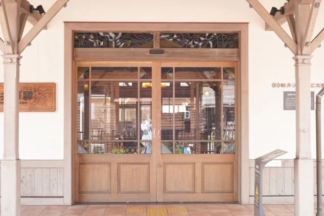  軽井沢にあるカフェやレストランの入り口。木製のドアにはステンドグラスがあしらわれ、おしゃれな雰囲気を演出。リゾートバイトの仕事場として、洗練された空間をアピール。