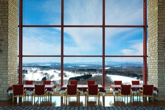 大きな窓から雪景色が一望できるホテルのレストランの画像。窓の外には広大な雪原が広がっており、テーブルと椅子が規則正しく並べられている。リゾートバイトの仕事内容を表す、ホテルのダイニングの画像。