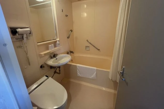 リゾートバイトの寮に備え付けられた、ユニットバスの画像。便座と洗面台、バスタブがまとまって配置されている。ドライヤーも備え付けられており、快適に利用できる。リゾートバイトの寮の風呂場の画像。