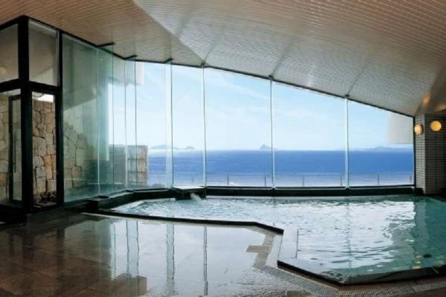 大きな窓から海が一望できる、ホテルの内湯の画像。床はタイル張りで、開放的な空間が広がっている。リゾートバイトの寮やホテルの福利厚生としても利用できる、温泉の画像。