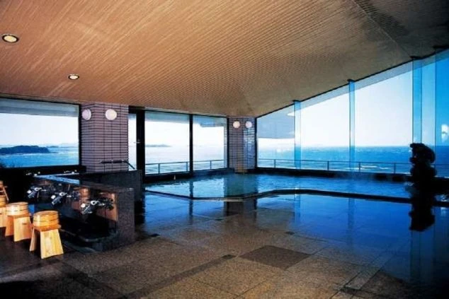 大きな窓から海が一望できる、ホテルの温泉の画像。床はタイル張りで、開放的な空間が広がっている。リゾートバイトの寮やホテルの福利厚生としても利用できる、温泉の画像。