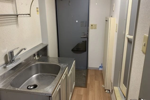 リゾートバイトの寮のキッチンの画像。シンクと収納スペースがあり、奥には玄関の扉が見える。リゾートバイトの寮の共用キッチンの画像。