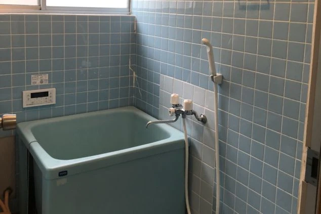リゾートバイトの寮にあるお風呂の画像。青いタイル張りの壁とバスタブ、シャワー付きで、湯船に浸かれる設備があることを示す。