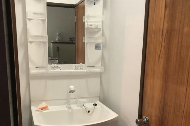 リゾートバイトの寮にある独立洗面台の画像。鏡付きの収納棚と洗面ボウルが一体化した清潔な設備。