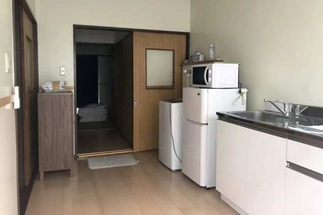 リゾートバイトの寮にあるキッチンの画像。冷蔵庫、電子レンジ、シンク、調理台、洗濯機が設置されている。
