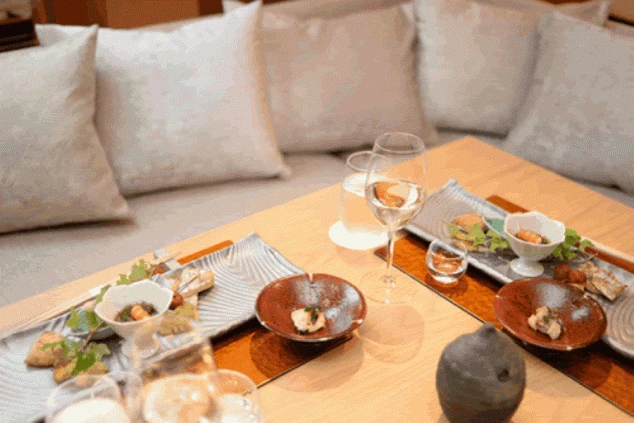 リゾートホテルのレストランで提供される料理の例。洗練された盛り付けの和食膳とグラスワインが並んでいる。リゾートバイトの食事（賄い）や、提供する料理の質が高いことをアピール。