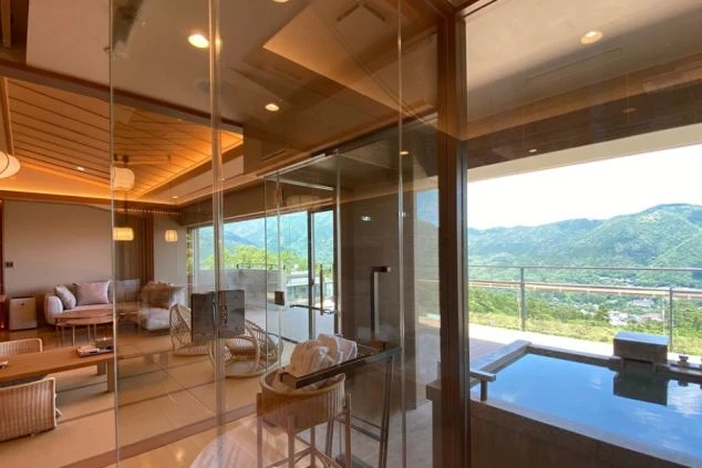 リゾートホテルの客室。大きな窓から山の景色が見え、室内には露天風呂も完備。開放感あふれるリゾートバイトの勤務地や客室の魅力を伝える。